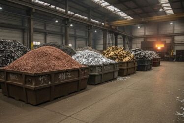 Resíduos metálicos não-ferrosos separados por tipo em galpão industrial de reciclagem, com forno de fundição ao fundo